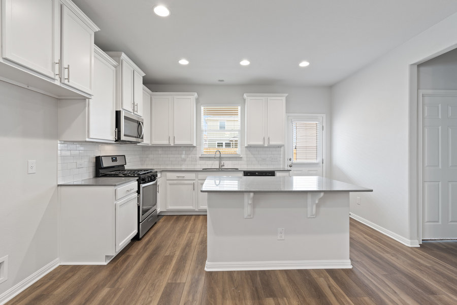 457 Elephant Island Loop Kyle, TX 78640 - Photo 4 of 30 a kitchen with stainless steel appliances white cabinets a sink and wooden floor