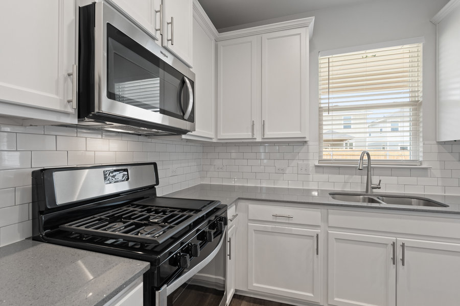 457 Elephant Island Loop Kyle, TX 78640 - Photo 8 of 30 a kitchen with granite countertop a sink a stove and cabinets