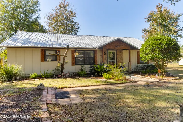 a living room with furniture two windows and wooden floor
