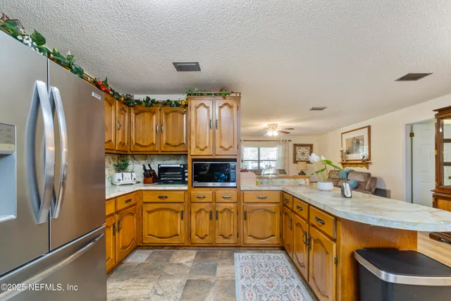 a dining hall with stainless steel appliances kitchen island granite countertop furniture and a kitchen view