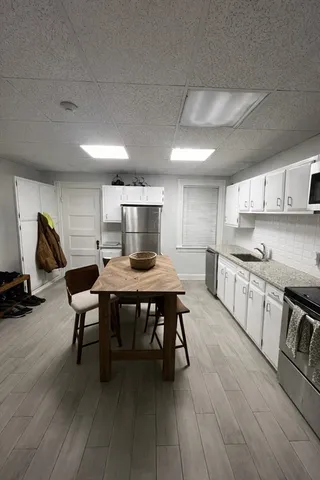 a kitchen with stainless steel appliances granite countertop a table chairs sink and cabinets