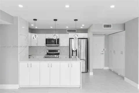 a large kitchen with stainless steel appliances kitchen island granite countertop a refrigerator and a stove top oven