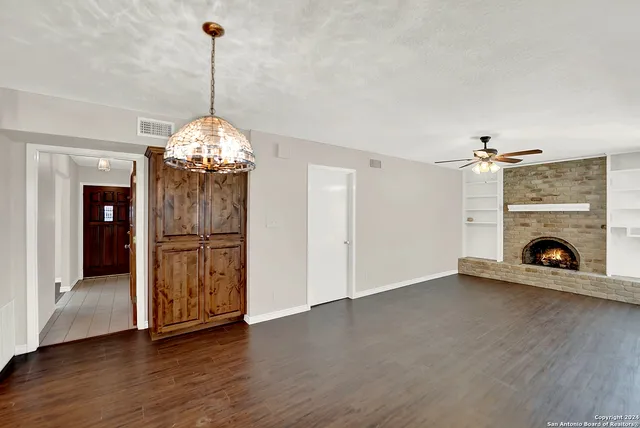 a view of a livingroom with a fireplace wooden floor and chandelier