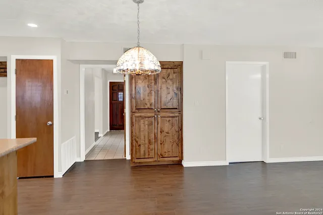a view of a refrigerator in kitchen and an empty room with wooden floor