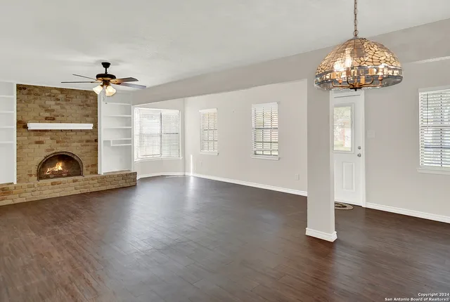 a view of a livingroom with a fireplace wooden floor chandelier and windows