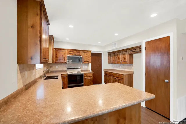a large kitchen with stainless steel appliances granite countertop a stove refrigerator and a kitchen island