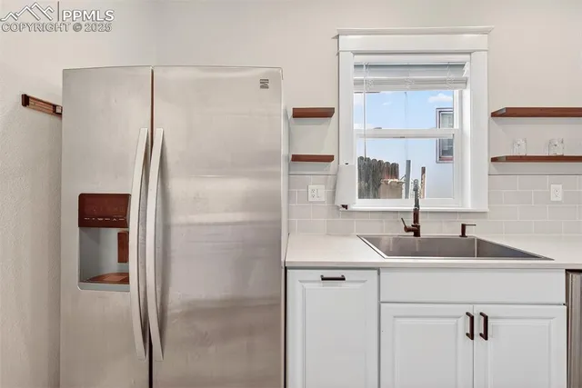 a kitchen with stainless steel appliances a refrigerator sink and white cabinets