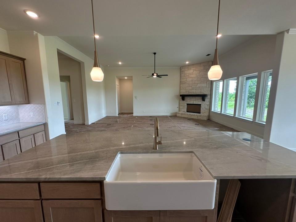 205 Cobb Road Leonard, TX 75452 - Photo 16 of 28 Kitchen island featuring a white apron-front sink, gold-finish faucet, and substantial stone countertop