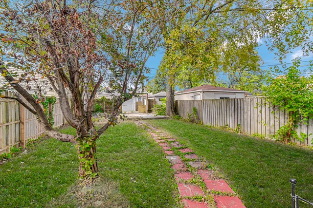 a view of a backyard with large trees and wooden fence