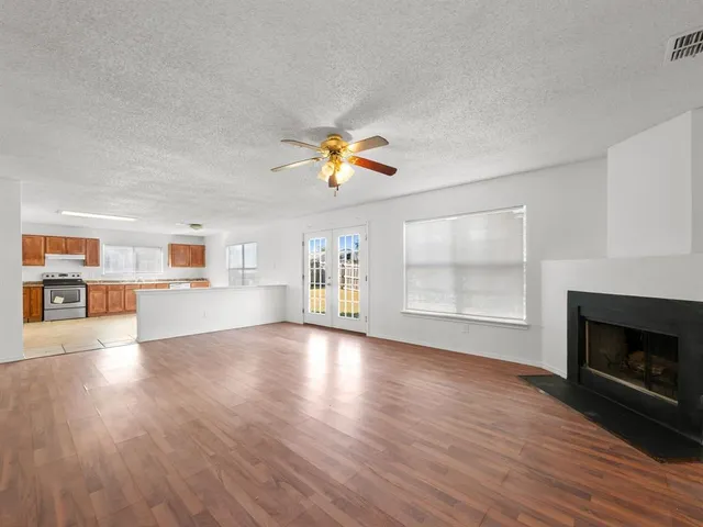 a view of an empty room with window and wooden floor
