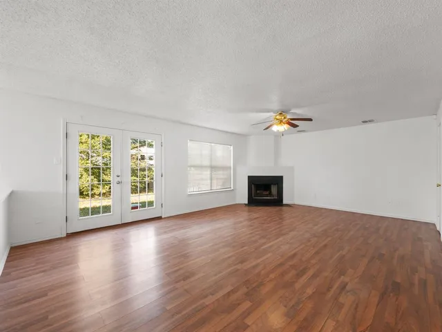 an empty room with wooden floor fireplace and windows