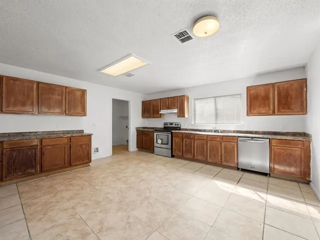 a large kitchen with a stove a sink a microwave and a refrigerator