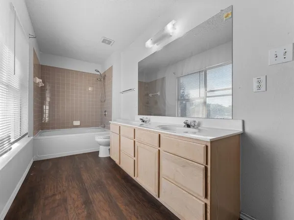 a bathroom with a granite countertop sink a toilet a bathtub and shower