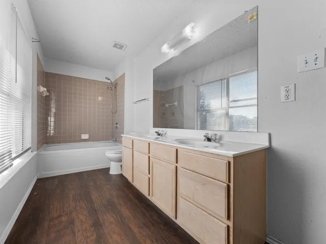 a bathroom with a granite countertop sink a toilet a bathtub and shower