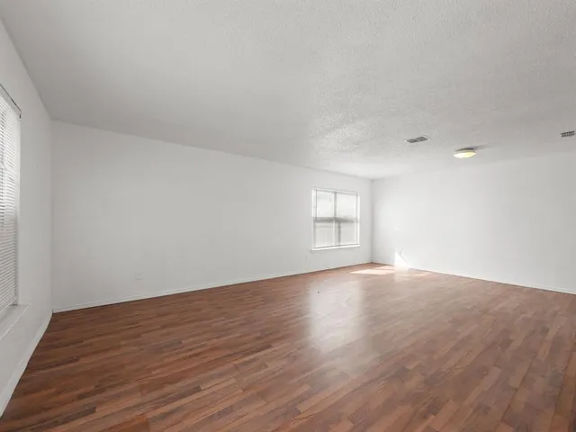 a view of an empty room with wooden floor and window