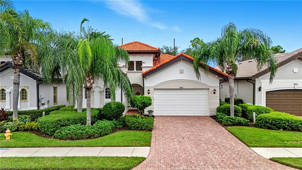 Mediterranean / spanish-style house with stucco siding, a tile roof, decorative driveway, a garage, and a front lawn