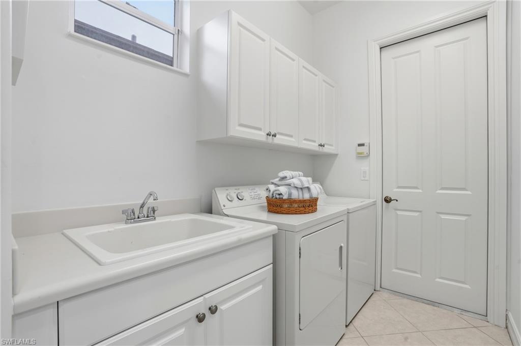 7840 Valencia Court Naples, FL 34113 - Photo 20 of 24 Laundry room featuring light tile patterned flooring, cabinet space, and washer and clothes dryer