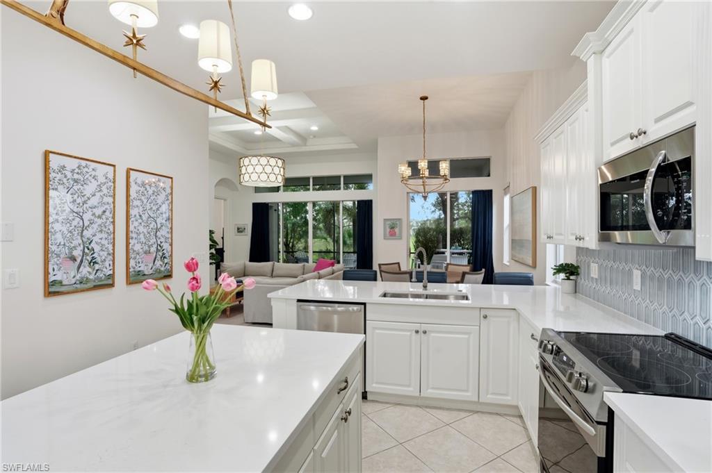 7840 Valencia Court Naples, FL 34113 - Photo 6 of 24 Kitchen featuring appliances with stainless steel finishes, white cabinetry, a peninsula, light tile patterned floors, and decorative light fixtures