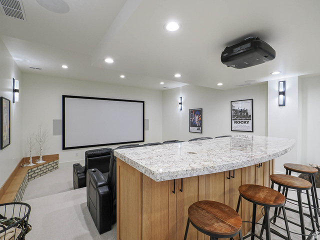 3167 South Mapleton Ests Drive Mapleton, UT 84664 - Photo 20 of 30 Curved stone-finish countertop bar with wood-finish paneling, recessed lighting, wall sconces, large projection screen, and a ceiling-mounted projector