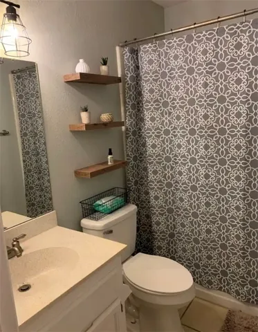 a bathroom with a sink a toilet and shower curtain