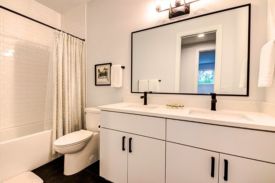 916 East 50th Street, Unit 1 Austin, TX 78751 - Photo 20 of 36 The secondary bathroom upstairs with a dual vanity, elongated toilet, large bathtub and tile all of the way to the ceiling.