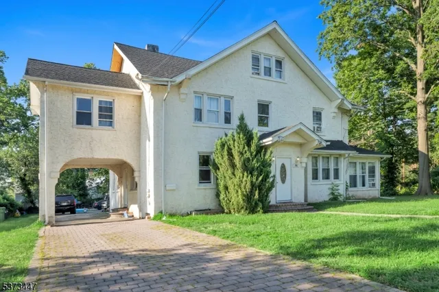 a view of a white house next to a yard with plants and trees