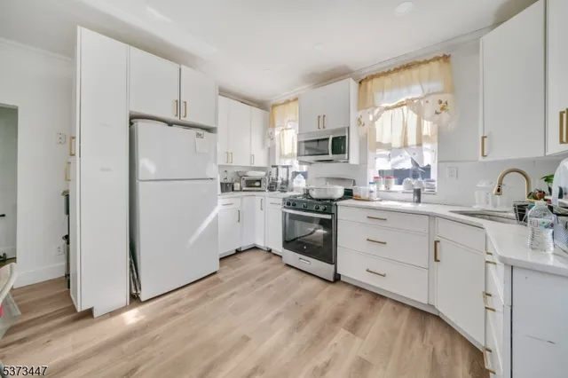 a kitchen with white cabinets white stainless steel appliances and sink