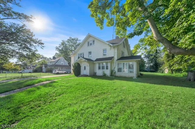 a view of a house with a big yard plants and large trees