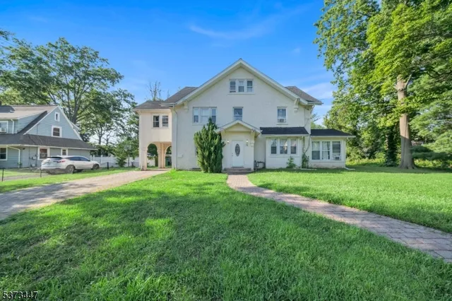 a view of a house with a big yard plants and large trees