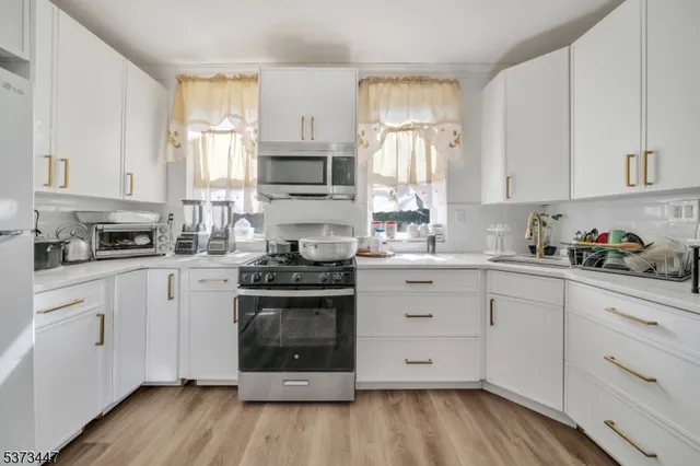 a kitchen with stainless steel appliances a white stove top oven cabinets and a window