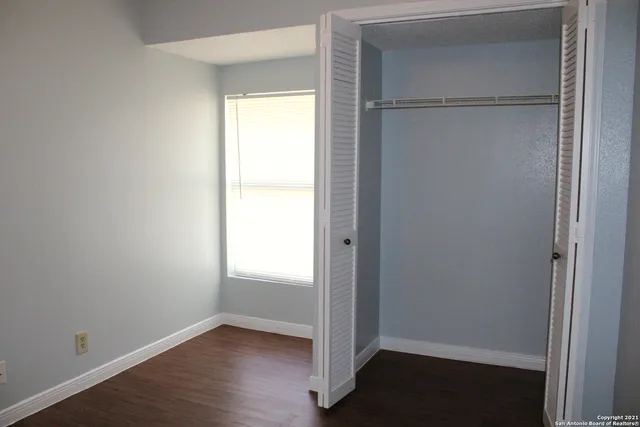 a view of an empty room with wooden floor and closet