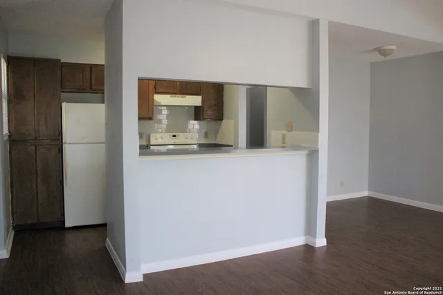 a kitchen with a refrigerator and wooden floor