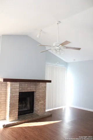 a view of an empty room with wooden floor fireplace and a window