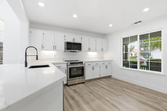 a kitchen with stainless steel appliances a stove top oven a sink a refrigerator a window