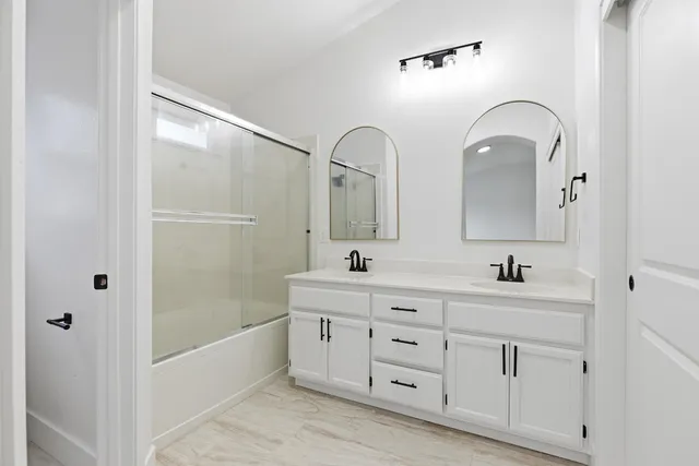 a bathroom with a double vanity sink mirror and bathtub
