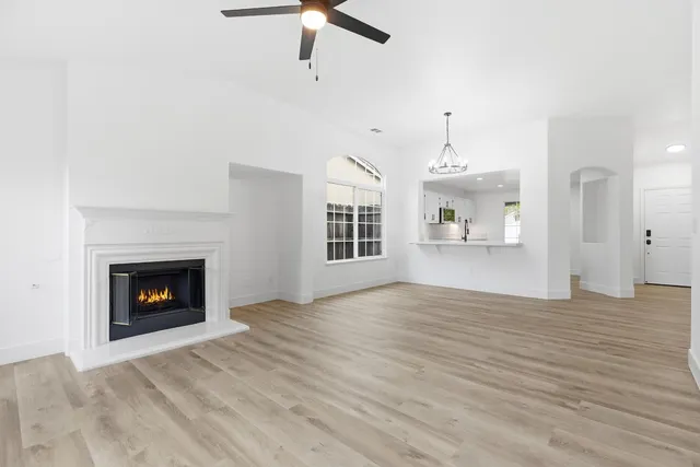 a view of an empty room with wooden floor fireplace and a window