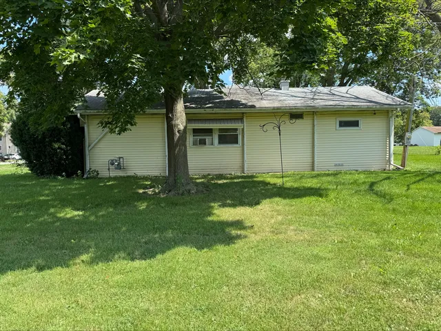 a view of a yard in front of a house with plants and large trees
