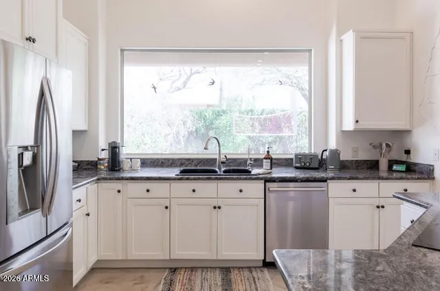 a kitchen with granite countertop a sink window and refrigerator