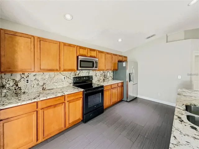 a kitchen with stainless steel appliances granite countertop a stove a sink and a refrigerator