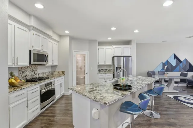 a kitchen with stainless steel appliances kitchen island granite countertop a stove refrigerator and cabinets