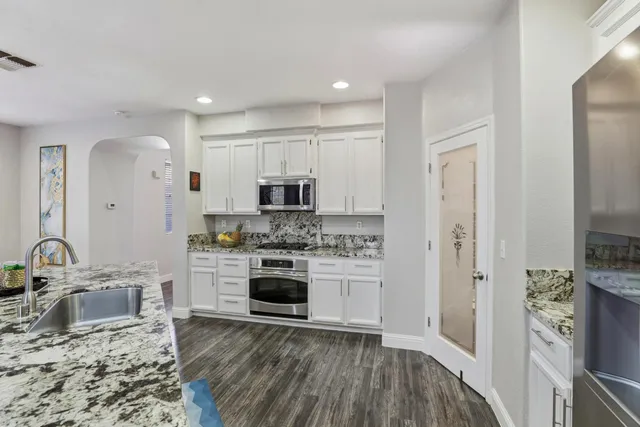 a kitchen with stainless steel appliances granite countertop a stove top oven a sink and a refrigerator