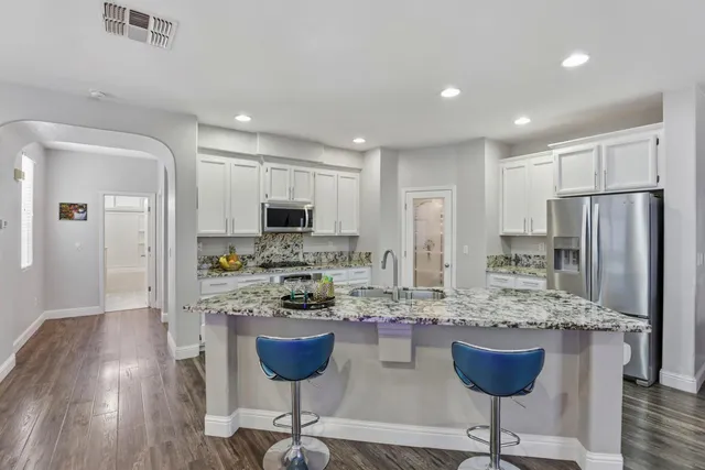 a kitchen with stainless steel appliances granite countertop a stove a refrigerator a sink a dining table and chairs