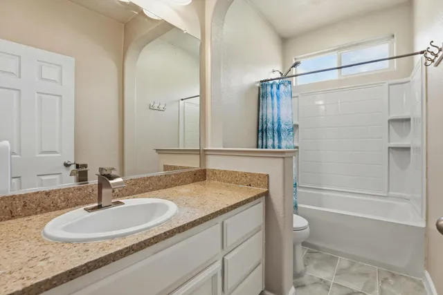 a bathroom with a granite countertop sink a toilet and a mirror