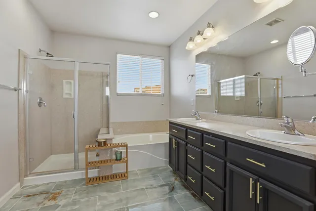 a spacious bathroom with a tub sink shower and mirror
