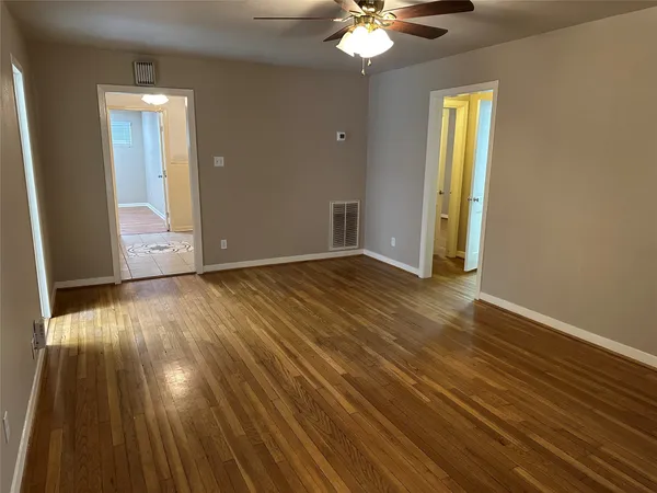 a view of an empty room with wooden floor and a window