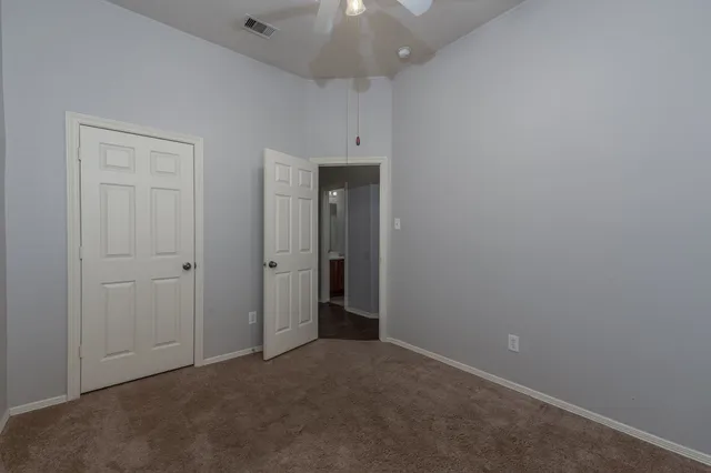 an empty room with chandelier fan and closet