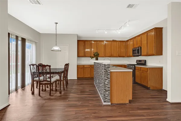a kitchen with stainless steel appliances granite countertop a stove top oven a sink dishwasher a dining table and chairs with wooden floor