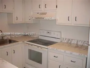 a kitchen with white cabinets and sink