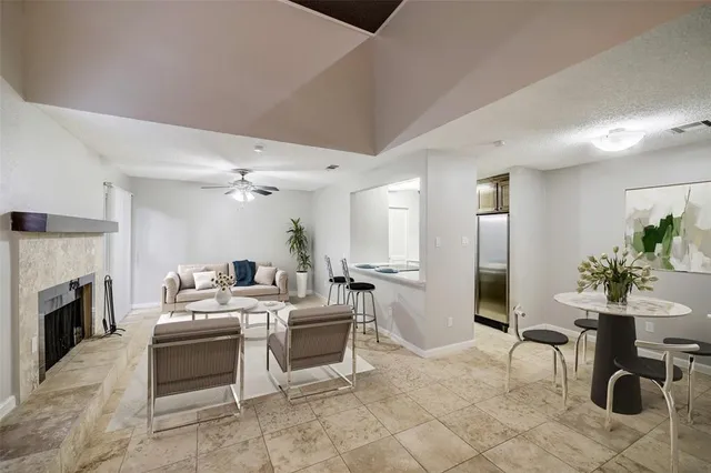 a living room with furniture a fireplace and a dining table with kitchen view
