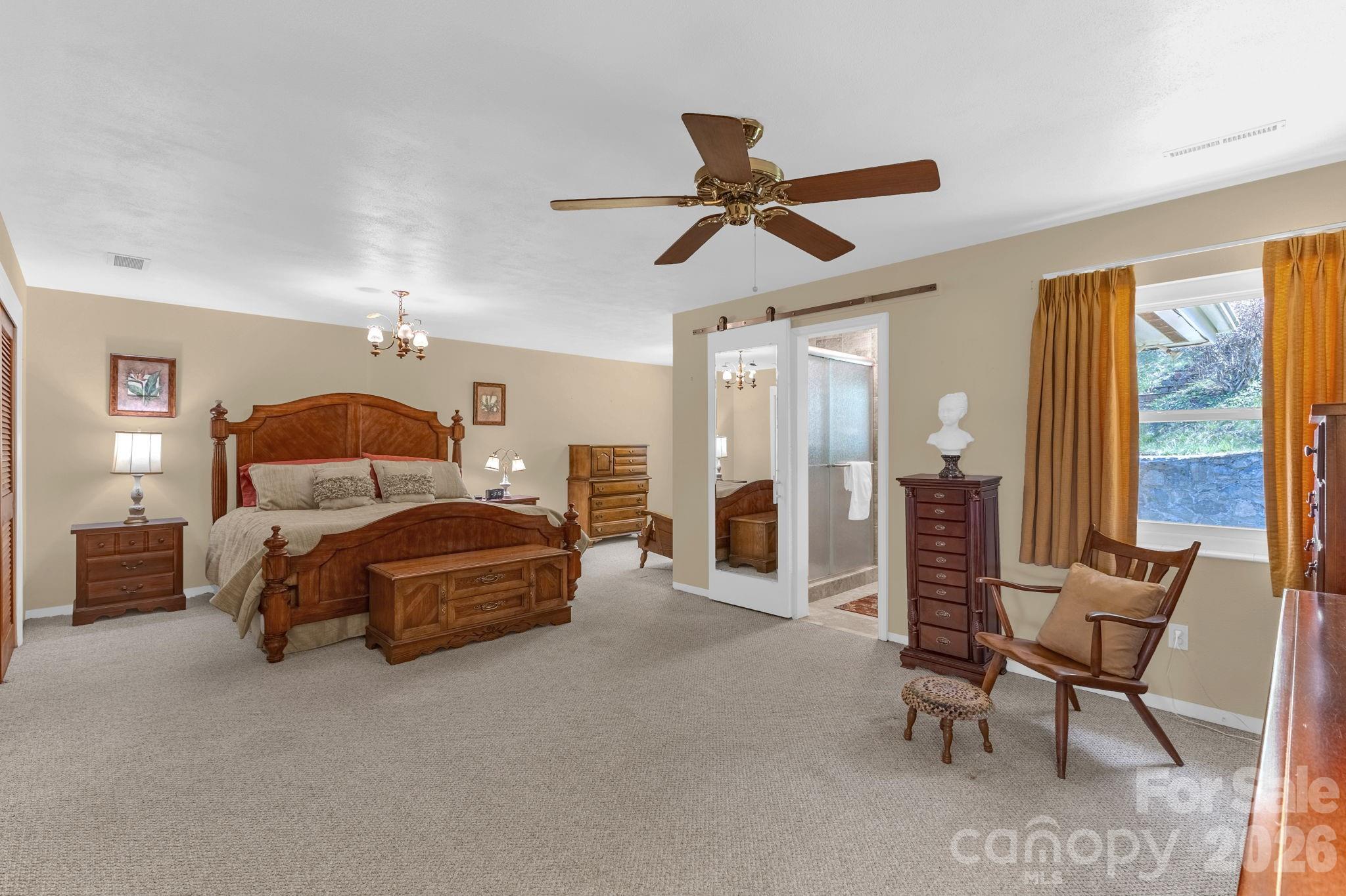 87 Rockwood Road Waynesville, NC 28786 - Photo 20 of 45 a spacious bedroom with a bed a chandelier and large window
